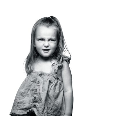 Black and white portrait of a playful young girl showing confidence and childhood charm.